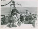 Image of Group on quarter deck; Stan at wheel, Miriam MacMillan, Andy, Dave, Horace, and Ed